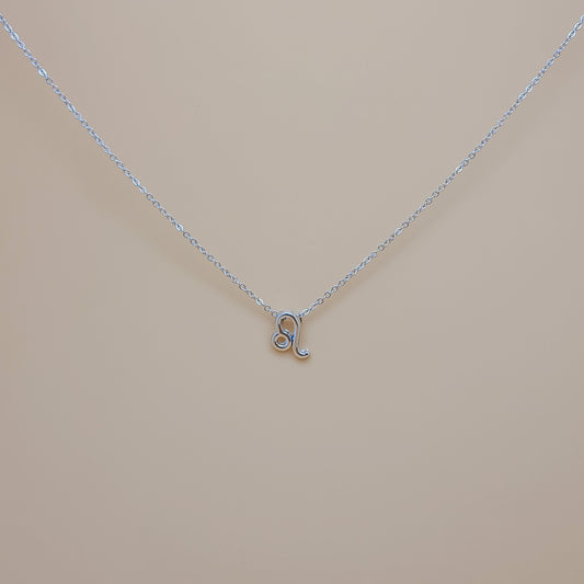 An image of a silver-plated pendant necklace with a Leo zodiac symbol on a delicate link chain. The necklace is displayed on a cream background with natural lighting that highlights its elegant design.